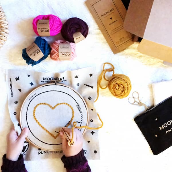 punch needle kit with Oxford needle, wooden frame and merino wool on embroidery fabric.