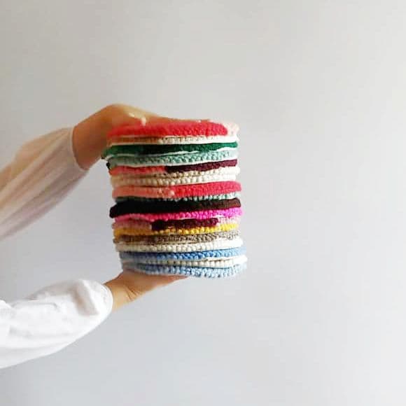 Stack of punch needle projects embroidered with Oxford needle and merino wool in different colors.